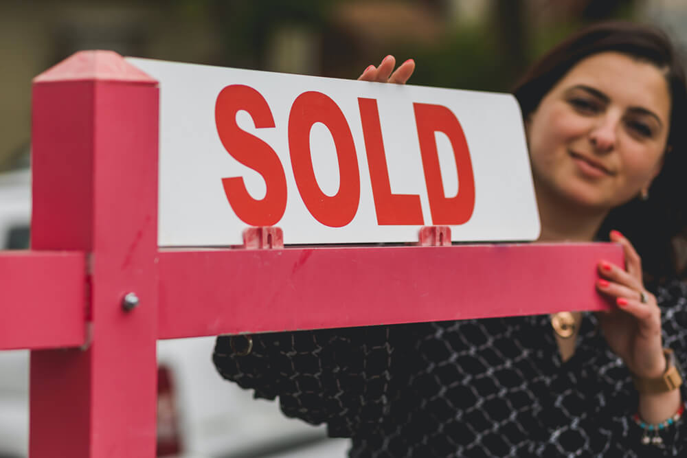 real estage agent holding sold sign